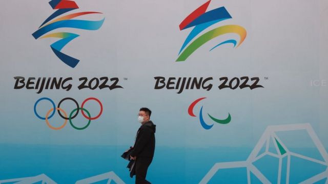 رجل يقف أمام لافتة اللأولمبياد.