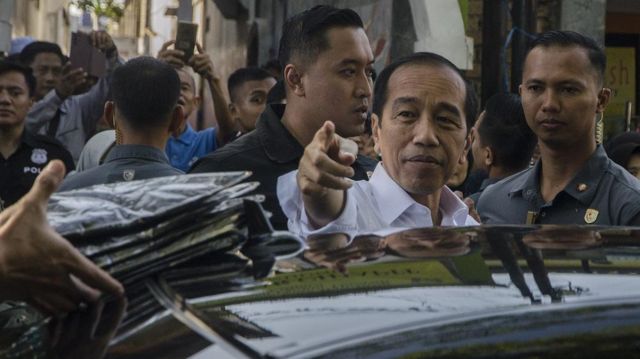 Presiden Joko Widodo (tengah) menunjuk warga untuk diberi kaos usai kunjungan di Pasar Cihapit, Bandung, Bandung, Jawa Barat, Rabu (12/7/2023). 