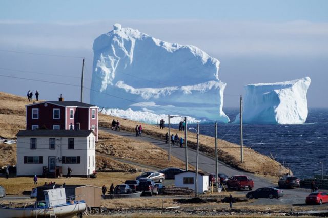 Residentes del pueblo observan el primer iceberg de la temporada.