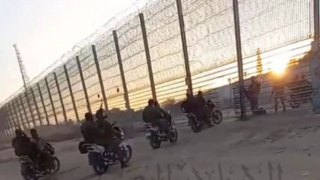 , pelo menos cinco motocicletas transportavam dois militantes armados com rifles, passando por um buraco cortado na cerca de arame da barreira.