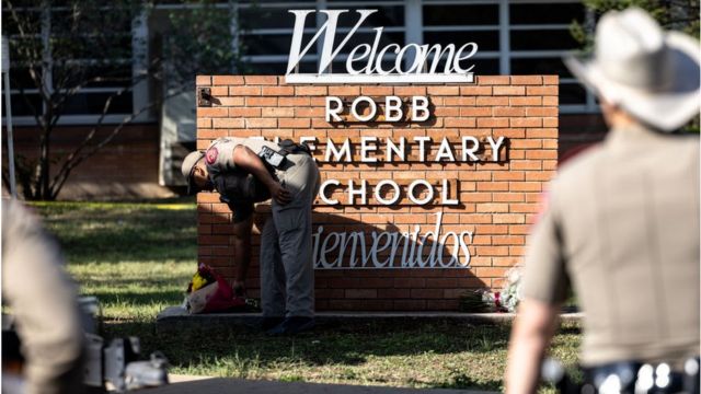 Un policía deja un ramo de flores en la entrada de la escuela primaria Robb en Uvalde, Texas.
