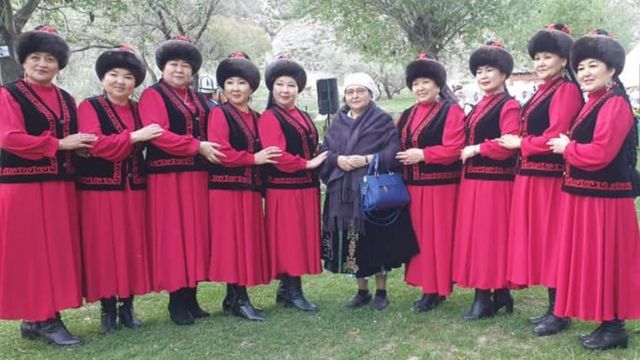 Ainuru Altybaeva debout avec un groupe de femmes en costume traditionnel