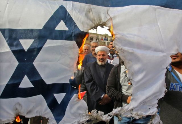 Manifestantes queman una bandera israelí durante una manifestación organizada por Hezbolá en las calles de la ciudad de Sidón, en el sur de Líbano.