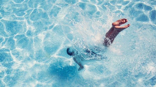 Homme plongeant dans une piscine