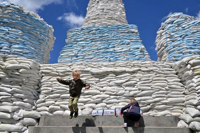 Enfants sautant et jouant autour d'un mur de sacs de sable