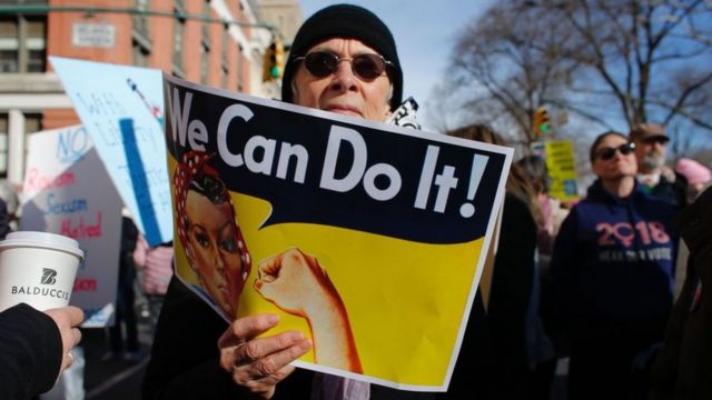 Un hombre sostiene una pancarta con la clásica frase feminista "We Can Do It" (Podemos hacerlo) en una protesta por el día de la mujer en Estados Unidos.