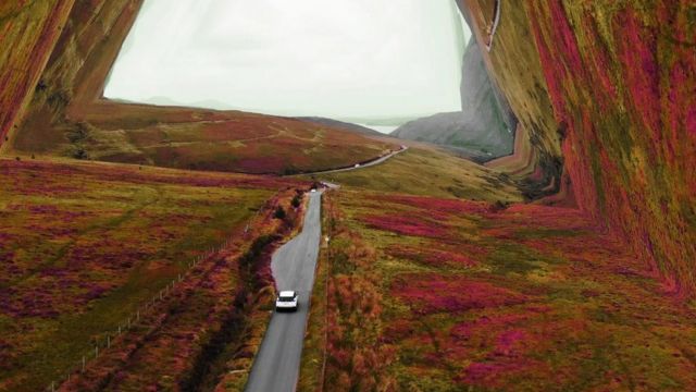 Carro em uma estrada em meio a paisagem montanhosa