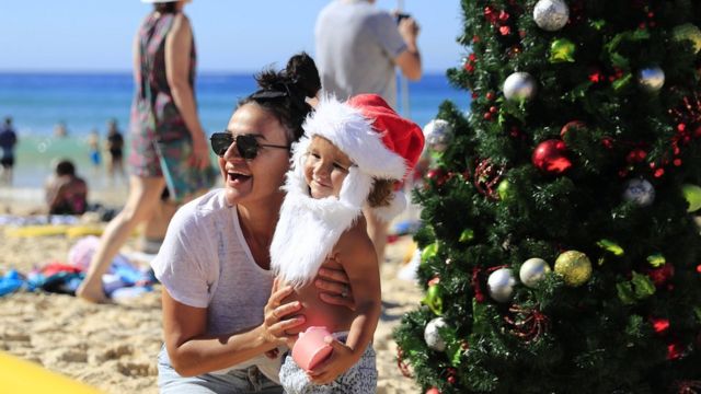 Families pose by a Christmas tree on Bondi Beach on December 25, 2018