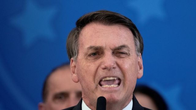Jair Bolsonaro fala no microfone em coletiva de imprensa, com ministros atrás