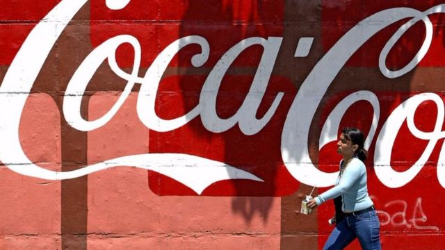 Una mujer cruza frente a un letrero de Coca Cola en Venezuela, durante protestas contra la empresa Femsa en 2006