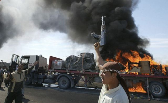 2004'te Felluce'de Iraklı Sünni Müslüman isyancılar, ateşe verilen ABD konvoyu önünde