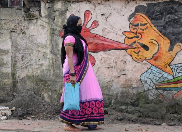 سيدة تمشي أمام لوحة غرافيتي في مومباي. استخدم هذا الفن في إطار حملة للتوعية من مخاطر البصق في الأماكن العامة