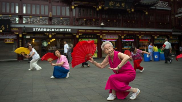 Women do morning exercises in front of a Starbucks restaurant on July 24, 2014 in Shanghai