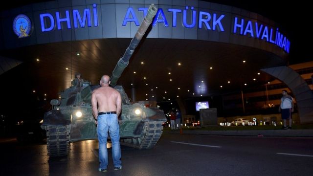 A man stands in front of a Turkish army tank at Ataturk airport in Istanbul