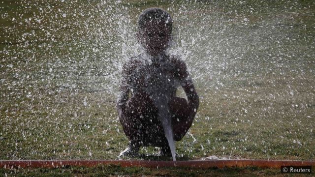 Criança se refresca com mangueira