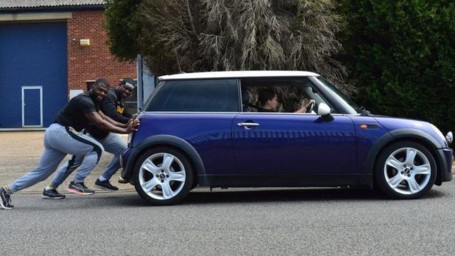 Two members of the Jamaican 4-man bobsleigh team push a Mini Cooper during lockdown in the UK