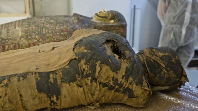 A múmia é vista deitada no lugar por um invólucro