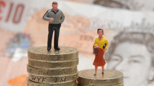 Plastic models of a man and woman stand on a pile of coins and bank notes