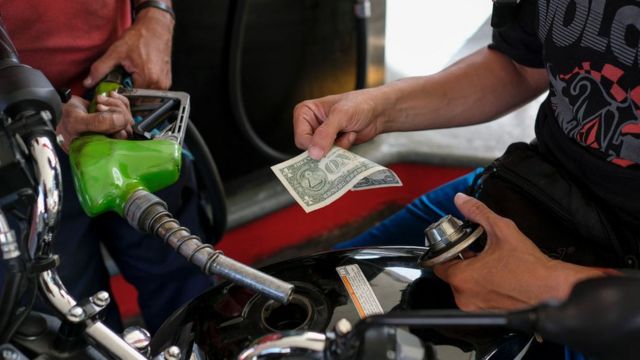 Homem pagando gasolina com nota de dólar