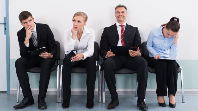 Cuatro personas sentadas esperando por una entrevista de trabajo