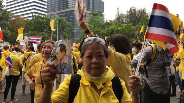 Protesters in yellow shirts hold a postcard of King Rama IX