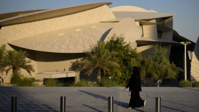 Seorang wanita berjalan di dekat Museum Nasional Qatar