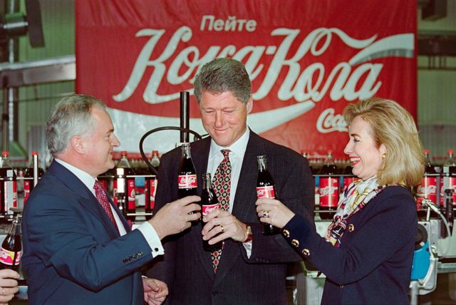 El presidente estadounidense Bill Clinton (centro), la primera dama Hillary Clinton (derecha) y Michael O'Neill, subgerente regional de Coca-Cola en Rusia (izquierda), beben una Coca-Cola el 11 de mayo de 1995, en Moscú, durante una visita a la fábrica de Coca-Cola en la capital rusa.