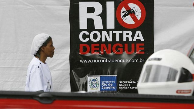 Una enfermera pasa frente a un cartel que alerta contra el dengue en Río de Janeiro