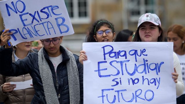 Adolescentes con carteles que dice "no existe planeta B" y "para qué estudiar si no hay futuro"