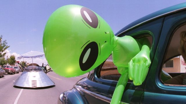 Un extraterrestre verde inflable en un auto.