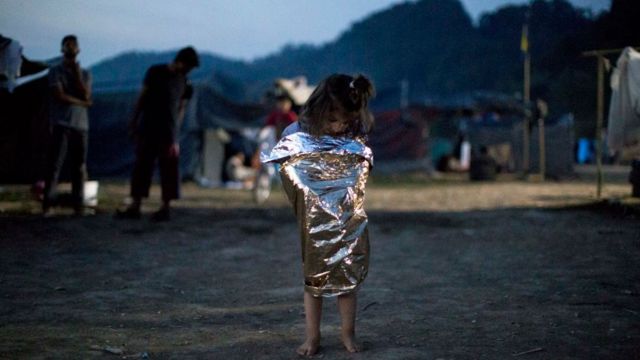 Ребенок-беженец, завернутый в спасательное одеяло