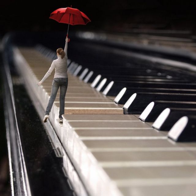 Mujer con paraguas caminando por las teclas de un piano