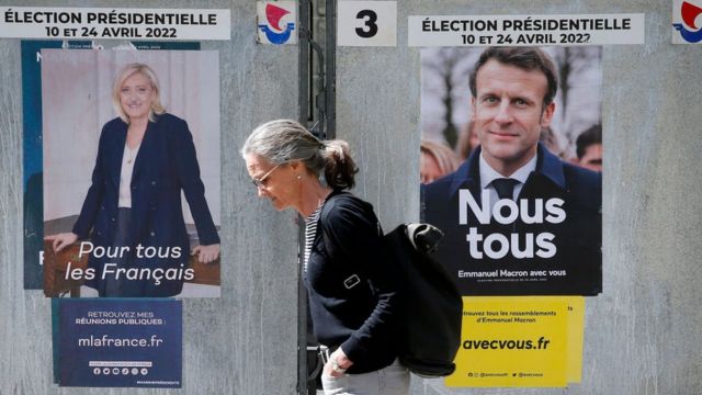 A woman walks past official campaign posters next to a polling station on April 20, 2022 in Paris, France.