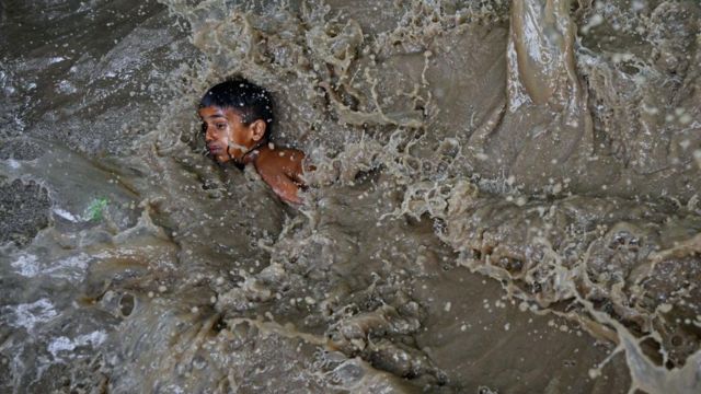 Seorang anak laki-laki terjebak genangan banjir tepi Sungai Yamuna yang meluap akibat akibat musim hujan