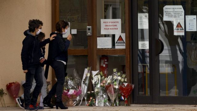 Parents and children lay flowers outside the school after teacher Samuel Paty was beheaded