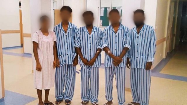 An image supplied by one of the migrants showing them in hospital clothing in Rwanda with a nurse, their faces blurred out to protect their identities