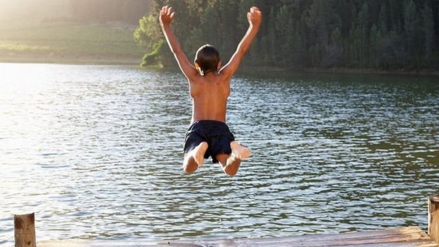 Young boy jumping into lake