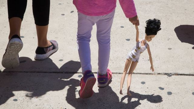 Una niña camina junto a una adulta.