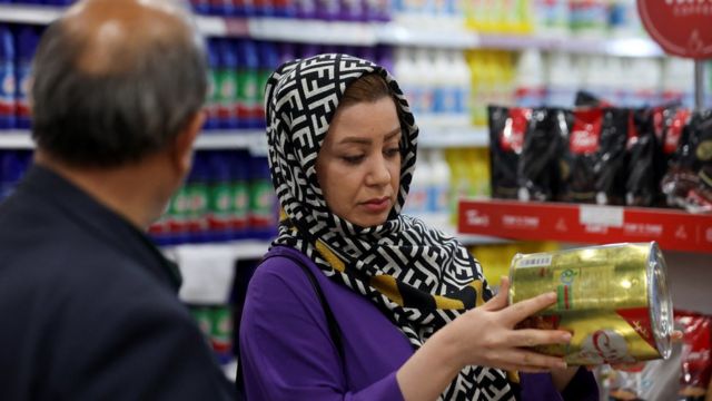 زنی در یک سوپرمارکت در تهران قیمت یک قوطی روغن نباتی را چک می‌کند