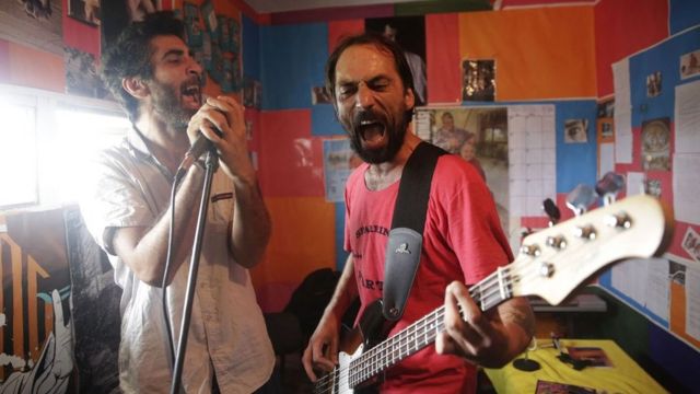 Dos reclusos cantan y tocan guitarra en el estudio de música