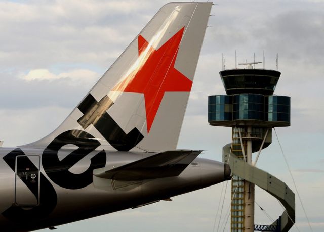 A plane from Qantas airline budget carrier Jetstar (L), is shown taxiing past the air traffic control tower (R) at Sydney Airport, 26 October 2007.