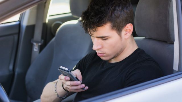 Homem usa celular enquanto dirige