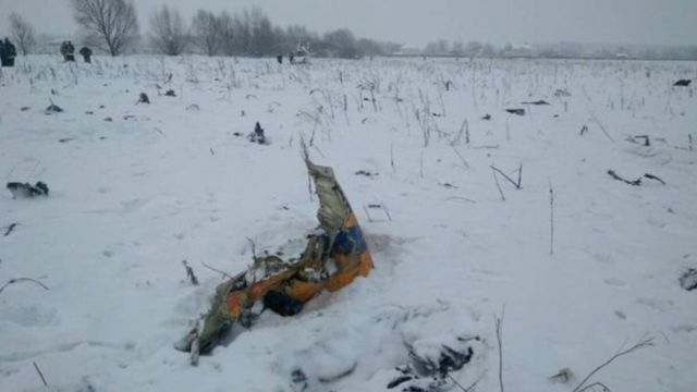На фотографиях с места катастрофы видны обломки самолета на заснеженном поле