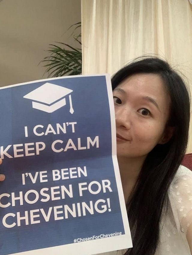 Huang memegang papan bertuliskan "Saya tidak bisa tetap tenang, saya telah dipilih untuk Chevening"