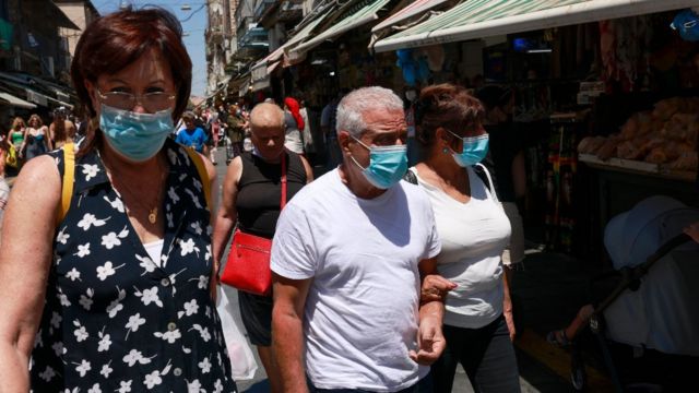 Personas caminando en la calle en Israel con mascarilla