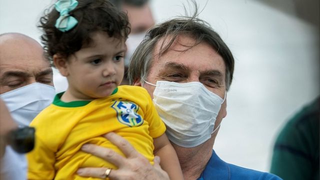 El presidente Jair Bolsonaro sostiene a una niña durante un rally en Brasilia, 17 de mayo 2020
