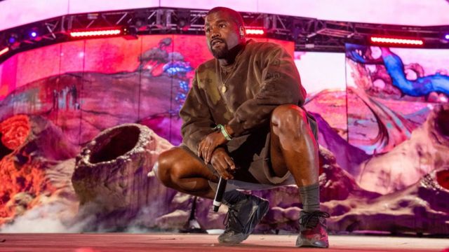 Kanye West crouched down on stage