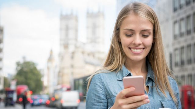 Mujer usando celular en las calles de Londres