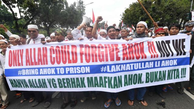 Protesters carry a banner saying "only Allah could forgive Ahok!!! Not we"