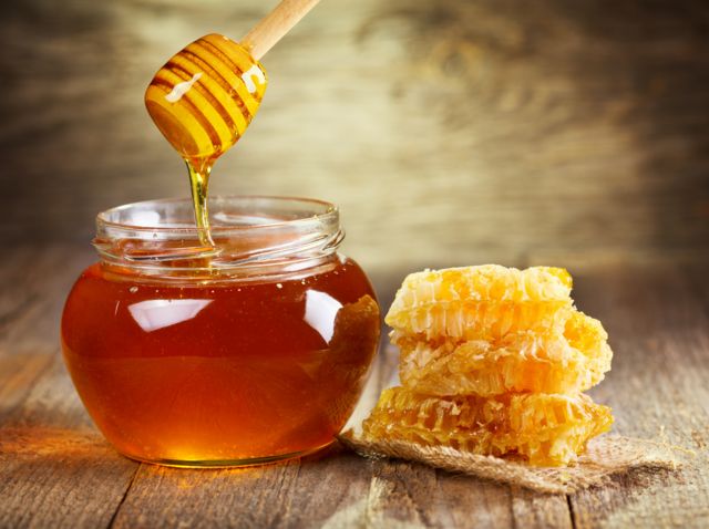 Pote de mel ao lado de favo de mel
